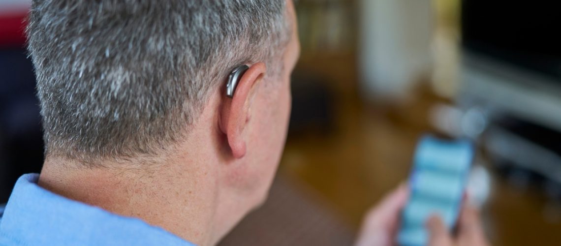 Close,Up,Of,Mature,Man,Wearing,Wireless,Hearing,Aid,Using