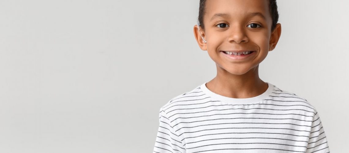 Little,African-american,Boy,With,Hearing,Aid,On,Light,Background