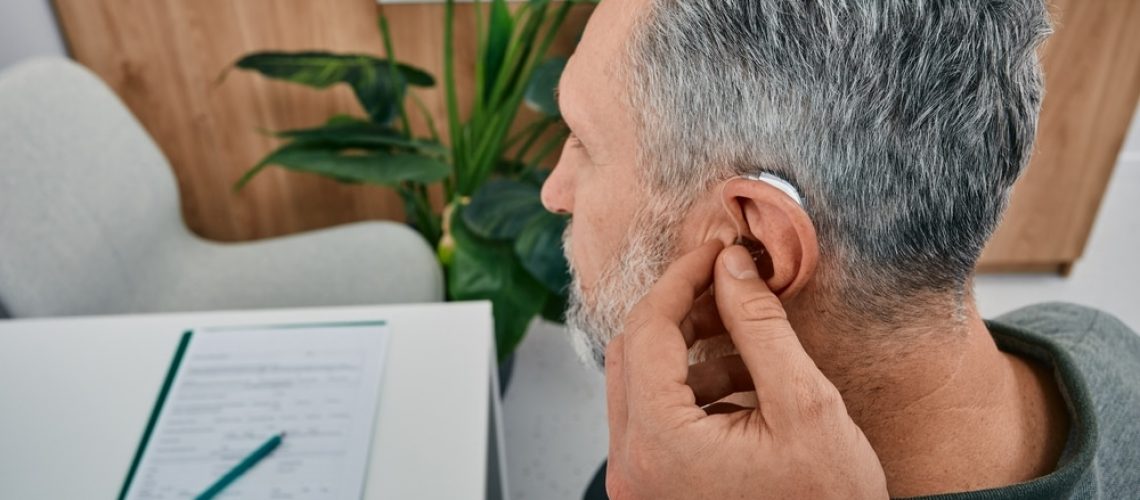 Audiologist,Fits,A,Hearing,Aid,On,Deafness,Mature,Man,Ear