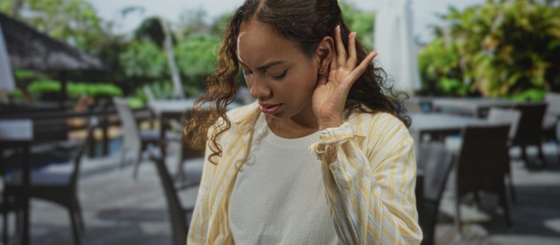 Woman,With,Hand,To,Ear,And,Furrowed,Brow,,Squinting,,Wearing